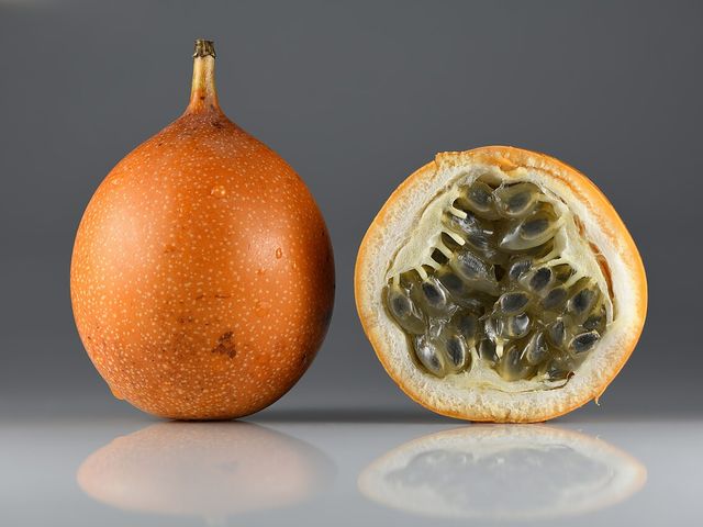 Granadilla entera y otra abierta con sus semillas